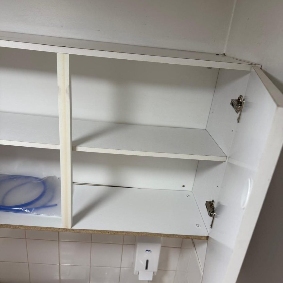 Commercial Cleaning | After Photo | Cupboards Empty white kitchen cupboard with missing shelves and visible hinges.