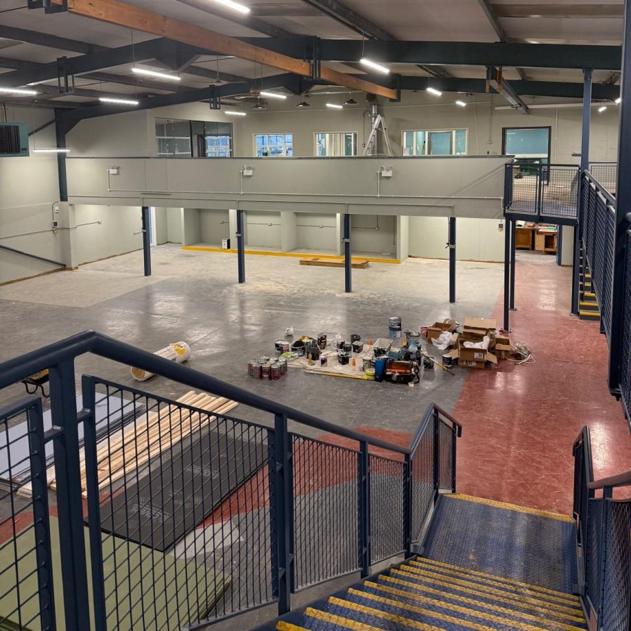 Commercial Cleaning | Before Photo | Dirty View of an empty industrial space with a staircase and organized items on the floor.
