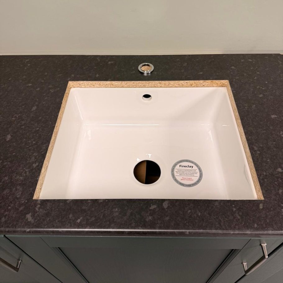 Commercial Cleaning – After Photo | Sink A modern, square, white sink set into a dark countertop with a drainage hole.