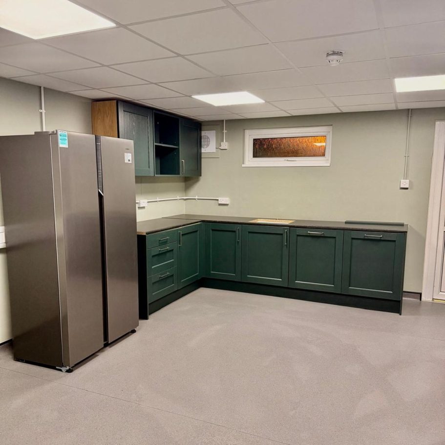 Commercial Cleaning – Industrial | After Photo | Kitchen Modern kitchen with dark green cabinets, grey flooring, and stainless steel refrigerator.