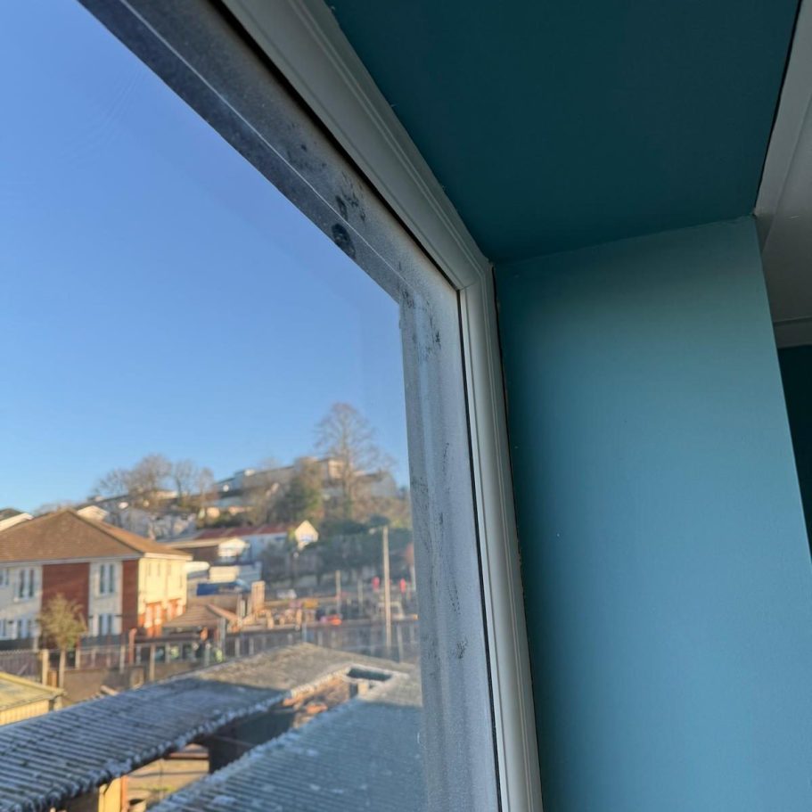 Commercial Deep Cleaning – Before Photo | Window Corner of a room with a blue wall, showing a view of a suburban landscape outside.