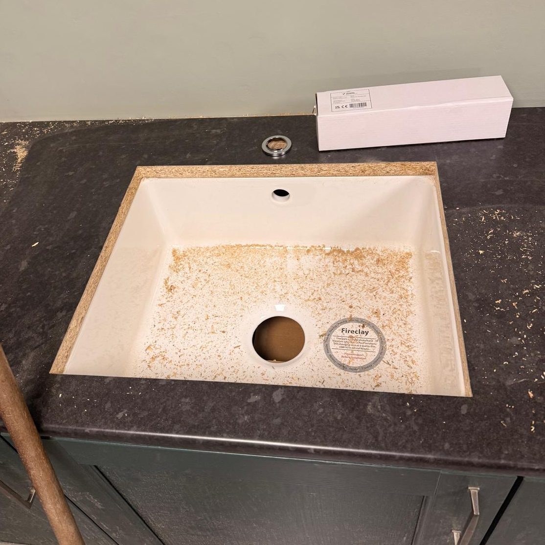 Commercial Cleaning – Before Photo | Sink A dirty, empty sink with debris on the countertop and a small box nearby.